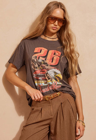 A woman wearing a faded brown graphic t-shirt with a large '26' and eagle print