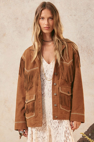 woman-wearing-a-brown-fringed-jacket-against-a-neutral-background